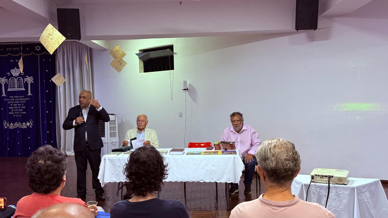 A mesa estão Wanderlei Silva e Mourad Belaciano, integrantes da equipe Beta Israel, em pé está jornalista Sionei Leão